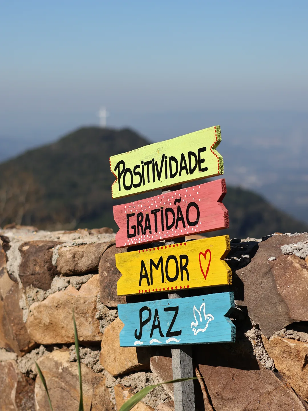 Placa com as palavras Positividade, Gratidão, Amor e Paz, com o cruzeiro ao fundo